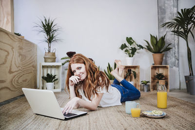 Young woman using phone while sitting on table