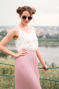 Portrait of young woman wearing sunglasses standing against clear sky