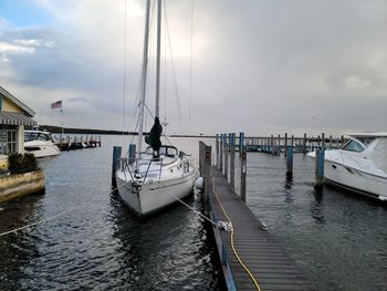 Sailboats moored in sea against sky