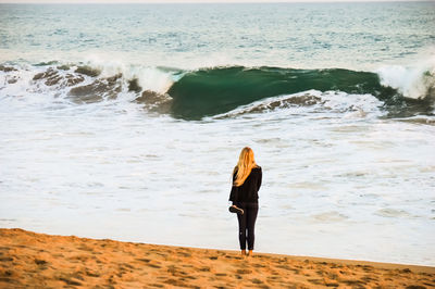 Rear view full length of woman standing at sandy beach