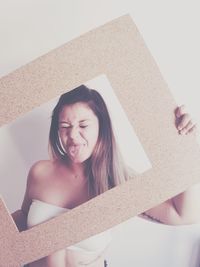 Close-up of woman holding picture frame against wall