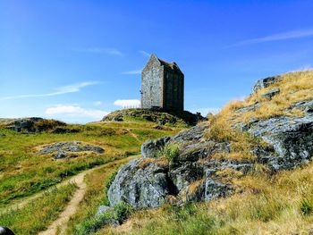 Old ruin building on field against blue sky