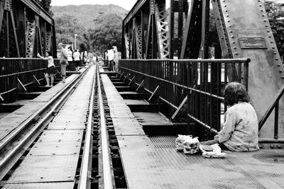 Rear view of female beggar sitting at railway bridge