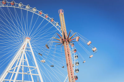 Low angle view of ferris wheel against clear blue sky