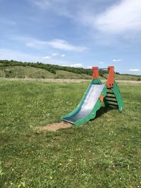 Deck chairs on field against sky