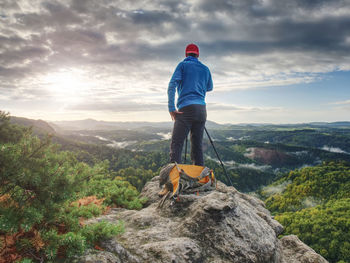 Rear view of man standing on rock against sky
