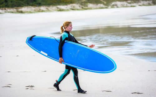 Full length of boy with surfboard on beach
