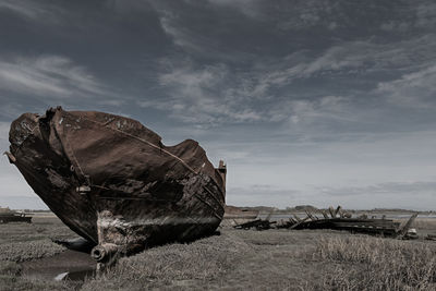 Abandoned boat on land against sky