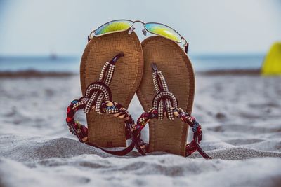 Footwear with sunglasses at sandy beach