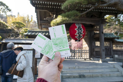 Cropped image of person holding paper against temple