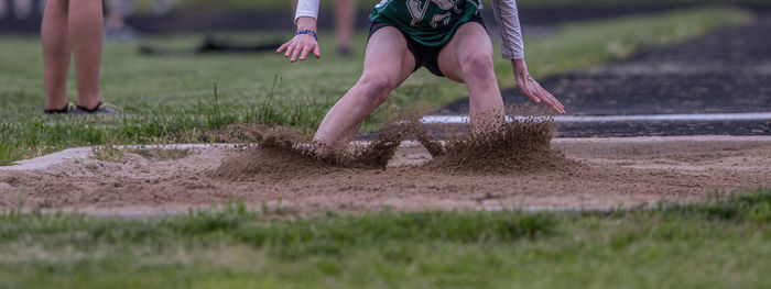 Full frame close-up view of a long jumper landing in the sand pit during a track meet