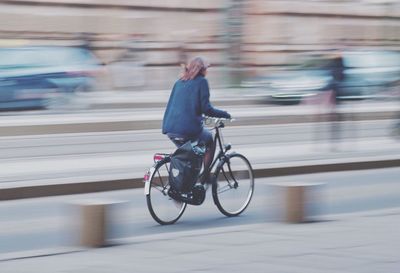 Man riding bicycle on road in city