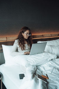 Young woman using mobile phone on bed