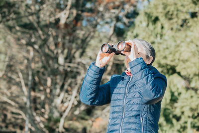 Man photographing through camera while standing outdoors