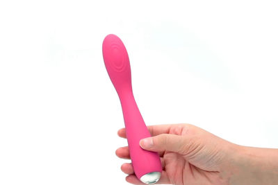 Close-up of hand holding pink over white background
