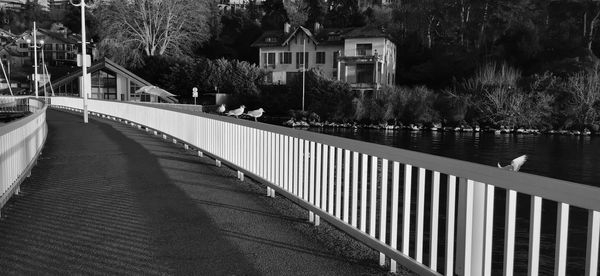 Footbridge over river amidst trees and buildings