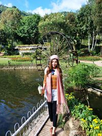 Portrait of woman standing by pond at park