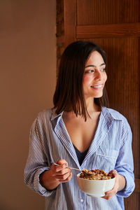 Young woman having breakfast next to a window at home