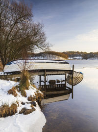 A tranquil winter scene with a boat moored near a jetty on the still lake.