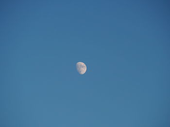 Low angle view of moon against clear blue sky