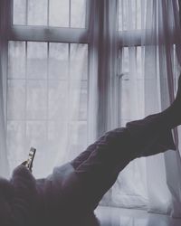 Low section of woman using mobile phone on bed