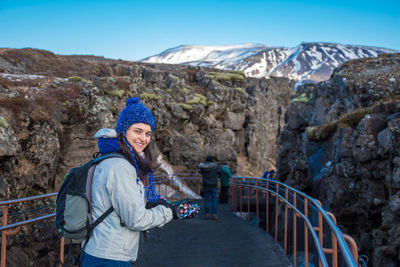 Portrait of woman standing on mountain against clear blue sky