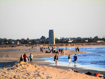 People at beach against clear sky