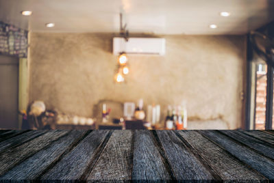 Close-up of wooden table with furniture and illuminated lighting equipment in background