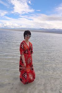 Woman standing in sea against sky