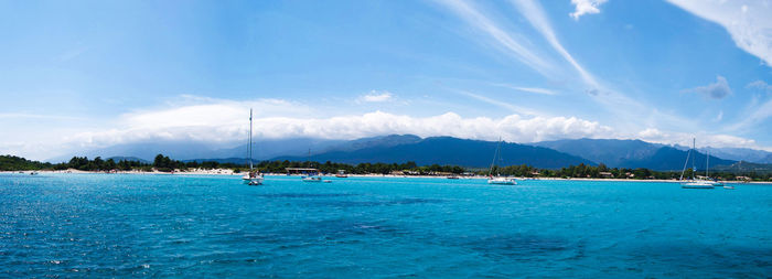 Boats in sea against cloudy sky