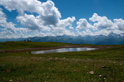 Scenic view of field by lake against sky