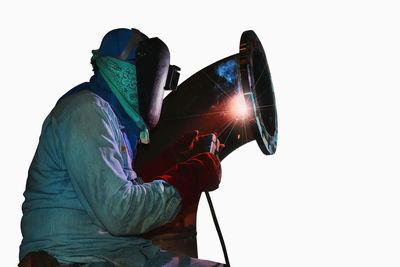 Side view of man holding camera against white background