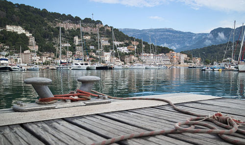 Sailboats moored on pier by lake against sky