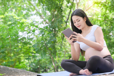 Full length of woman sitting on mobile phone