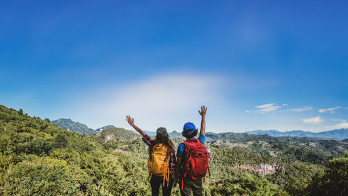 Rear view of man standing on mountain against clear blue sky