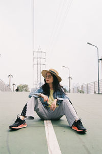 Young woman sitting in city against clear sky