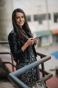 Cheerful young woman in dress and leather jacket smiling.