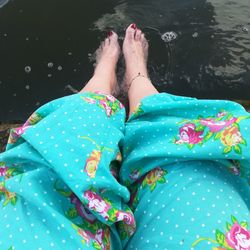 Low section of woman sitting by lake