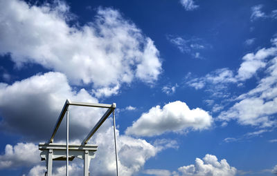 Upper white hinge of the lifting beams of a drawbridge in front  blue sky with white dramatic clouds