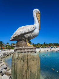 Sculpture of wooden post by sea against clear blue sky