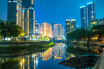 Illuminated bridge over river in city at night