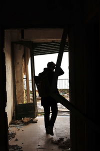 Rear view of silhouette man standing in window