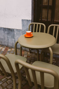 Empty chairs and coffee cup on table at sidewalk cafe