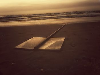 Close-up of beach against sky during sunset