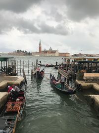 View of boats in canal against cloudy sky