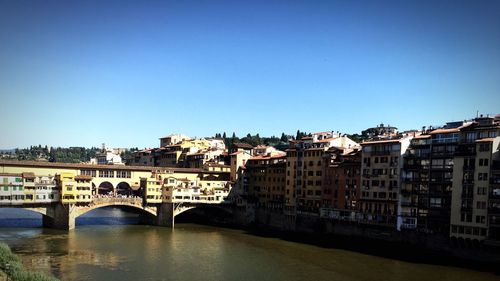 Bridge over river in city against clear sky