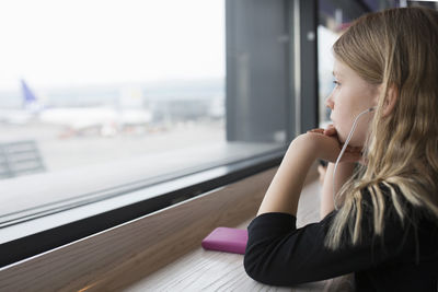 Thoughtful girl looking through window of restaurant