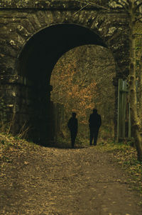 Rear view of people walking in tunnel