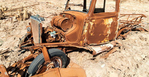 Old rusty wheel by abandoned car