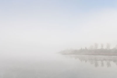 Scenic view of lake against sky during foggy weather